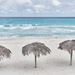 Atlantic sandy beach of Cuba, resort Varadero. Three palm leaf sun umbrellas